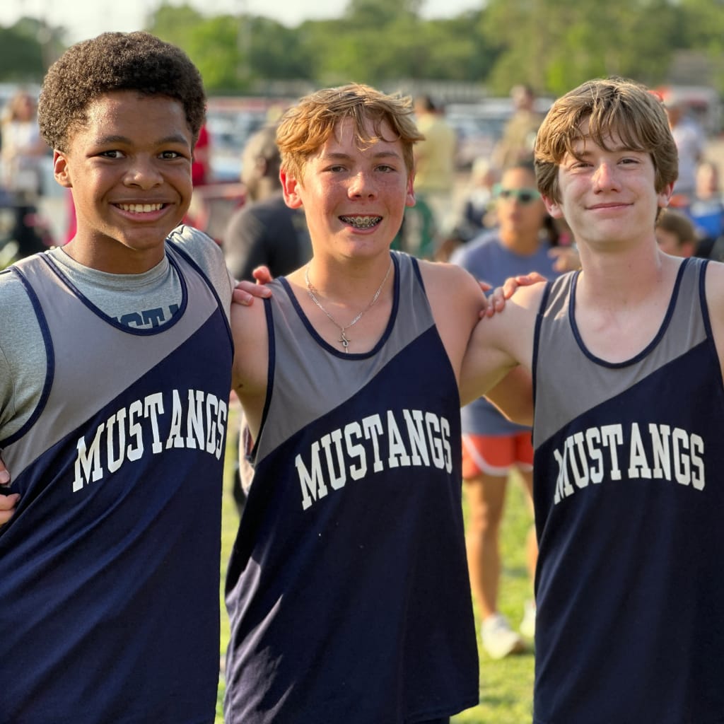 Three briarwood track athletes smile and have their arms around each other.