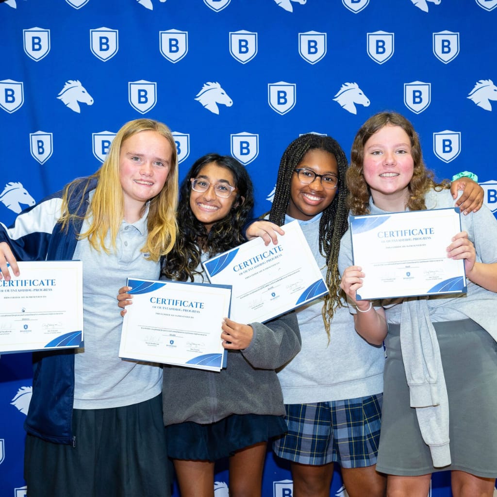 Briarwood students smile as they hold up paper certificates.