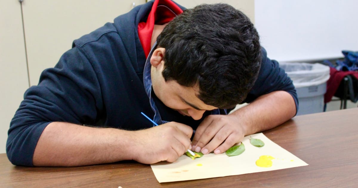 Tuttle student looks down while painting.