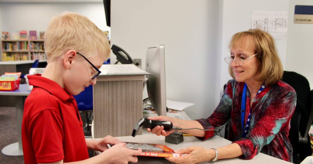 Tuttle student gets a booked checked out by librarian.