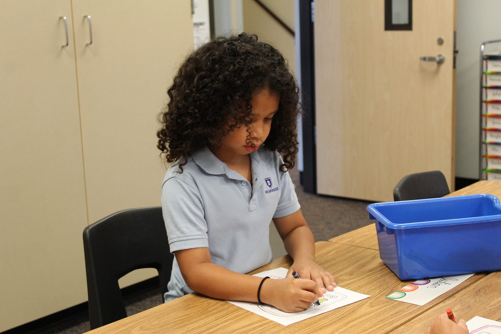 Student stands while writing on a piece of paper.