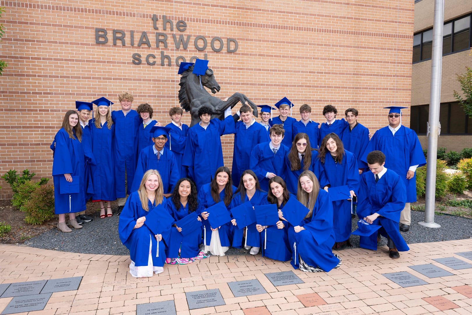 Photo of Briarwood graduates smiling while wearing matching blue graduation robes.