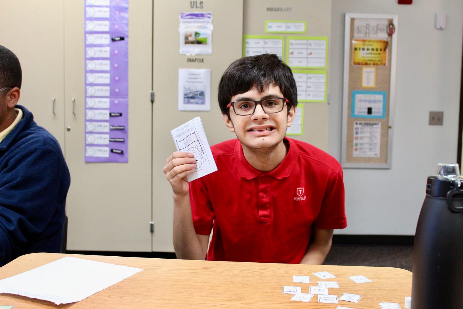 Student holds up a piece of paper while smiling.