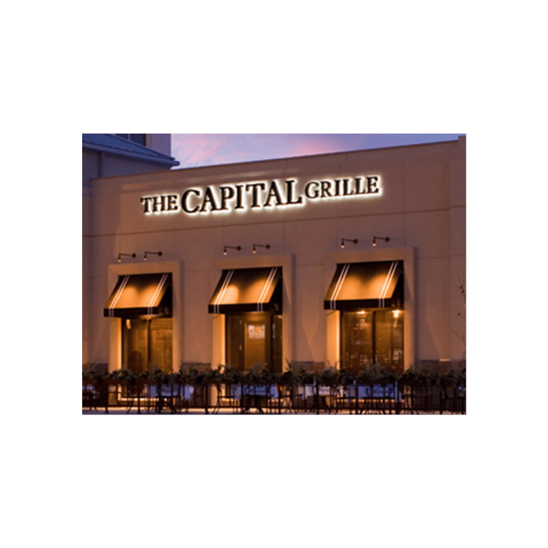 Brick building with words The Capital Grille lit up on the side.